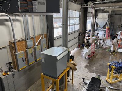 Industrial transformer install wide view showing distribution panels, feeders, and conduit work