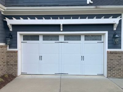 Upgraded exterior coach lights flanking residential garage doors