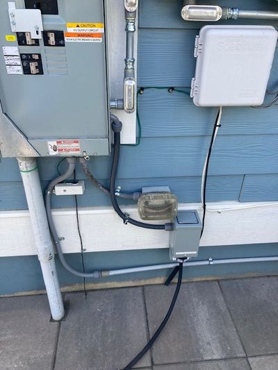 Residential generator interlock kit installed on exterior electrical panel with inlet box